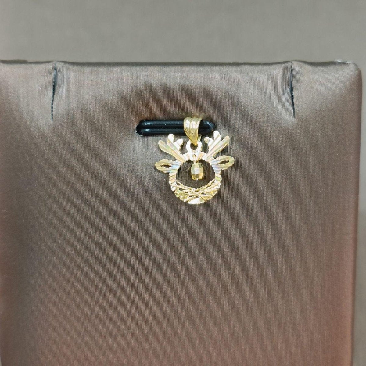Reference gold antler-shaped pendant with a dangling bead on a grey display
