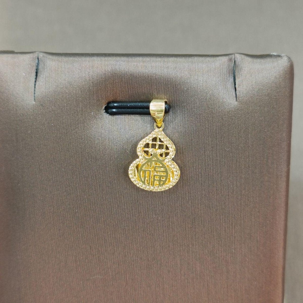 Reference gourd-shaped gold pendant with Chinese character detail on a grey display