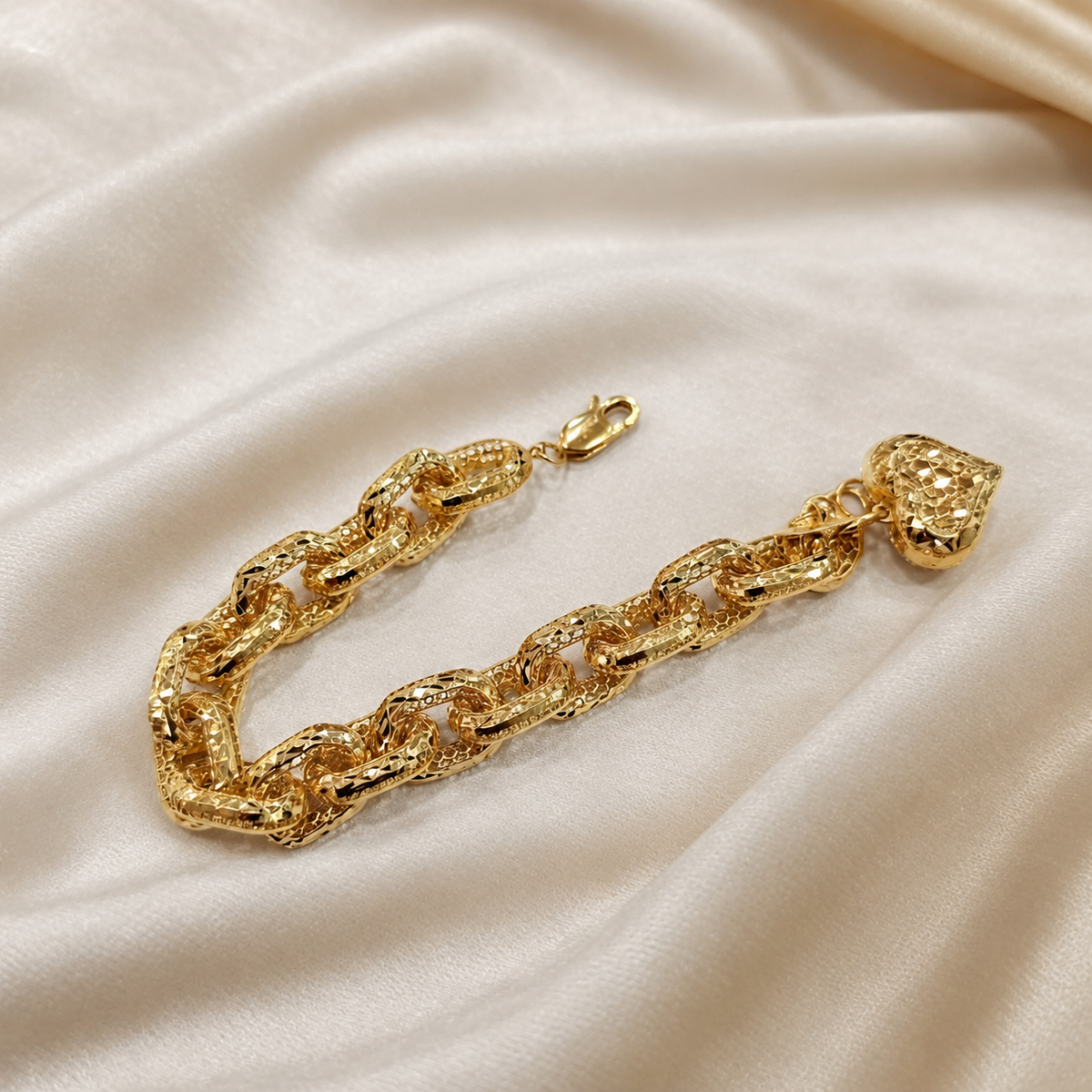 Gold reverse of the Regal Link Heart Charm Bracelet in a curved arrangement on cream satin