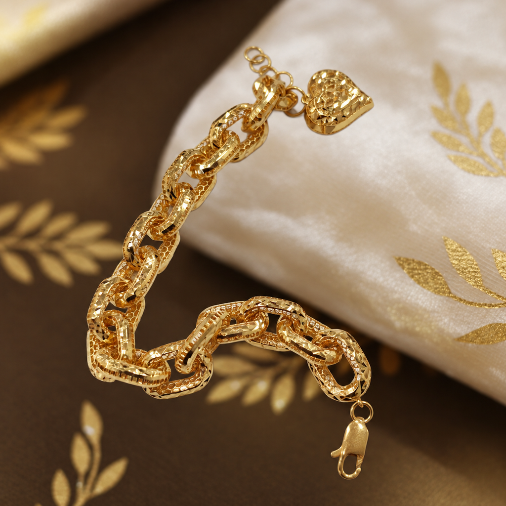 Close view of the 916 gold Regal Link Bracelet reverse, textured heart charm and lobster clasp beside a cushion