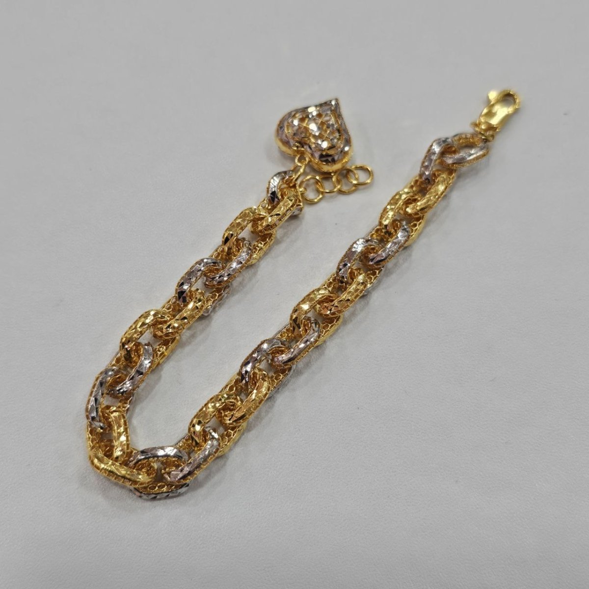 Original front view of the 916 gold Regal Link Bracelet in a U shape with two-tone links and heart charm