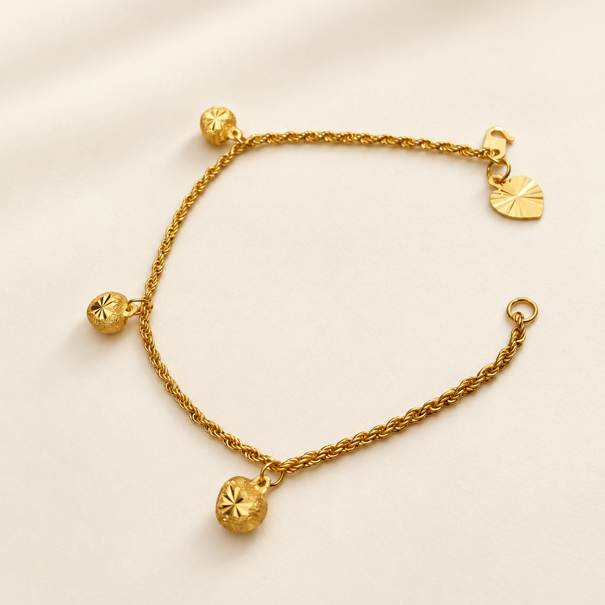Alternate full view of the 22K gold hollow rope bracelet with hook fastening and three textured charms