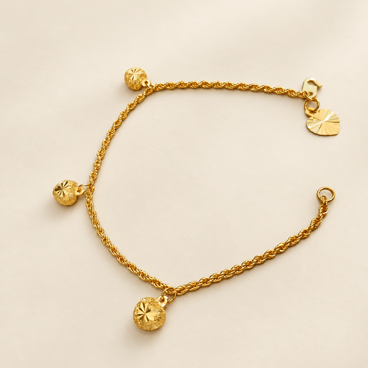 Angled view of the 22K gold hollow rope bracelet showing textured charms, starburst facets and twisted links