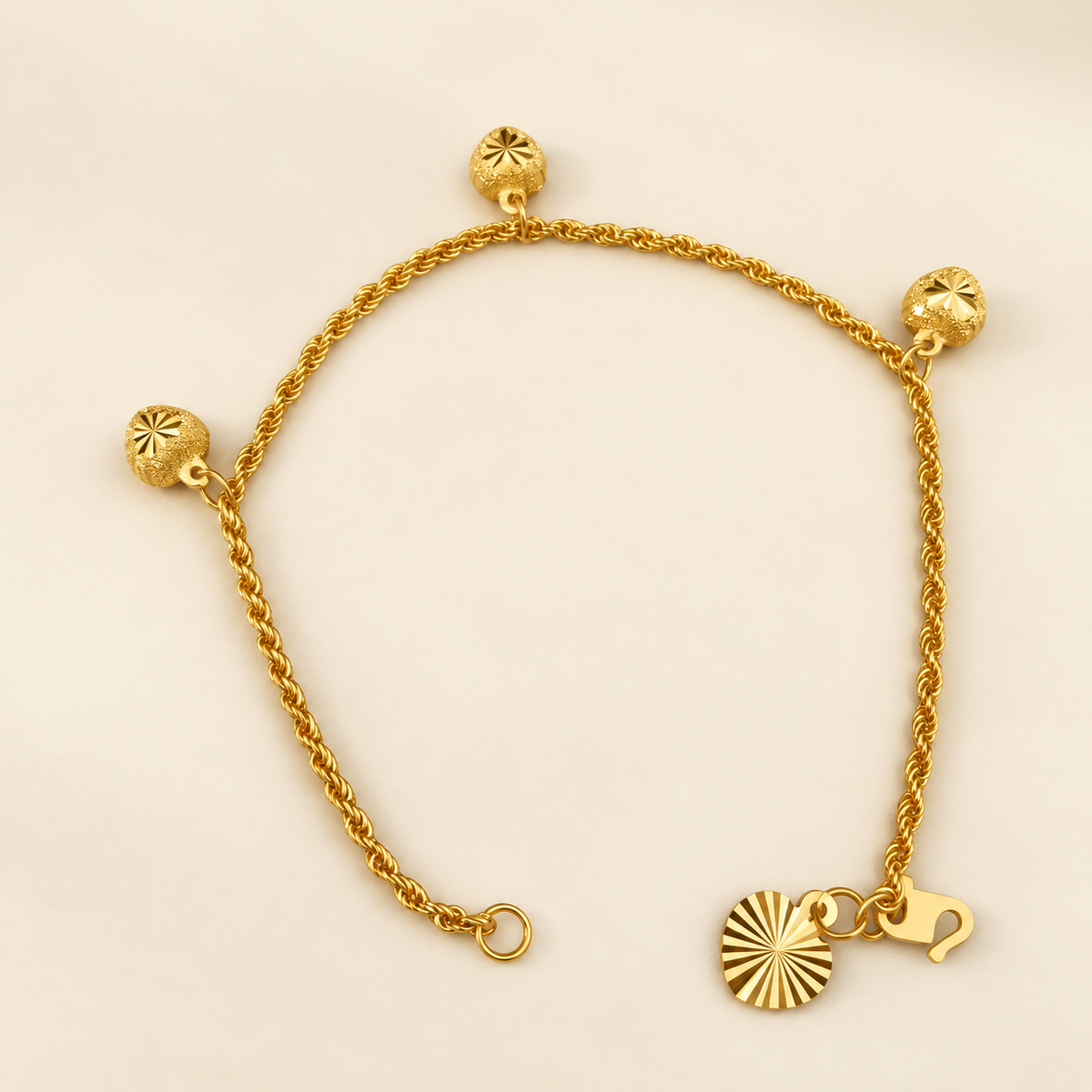916 gold hollow rope bracelet showing its hook clasp, flat end tag and three dangling charms