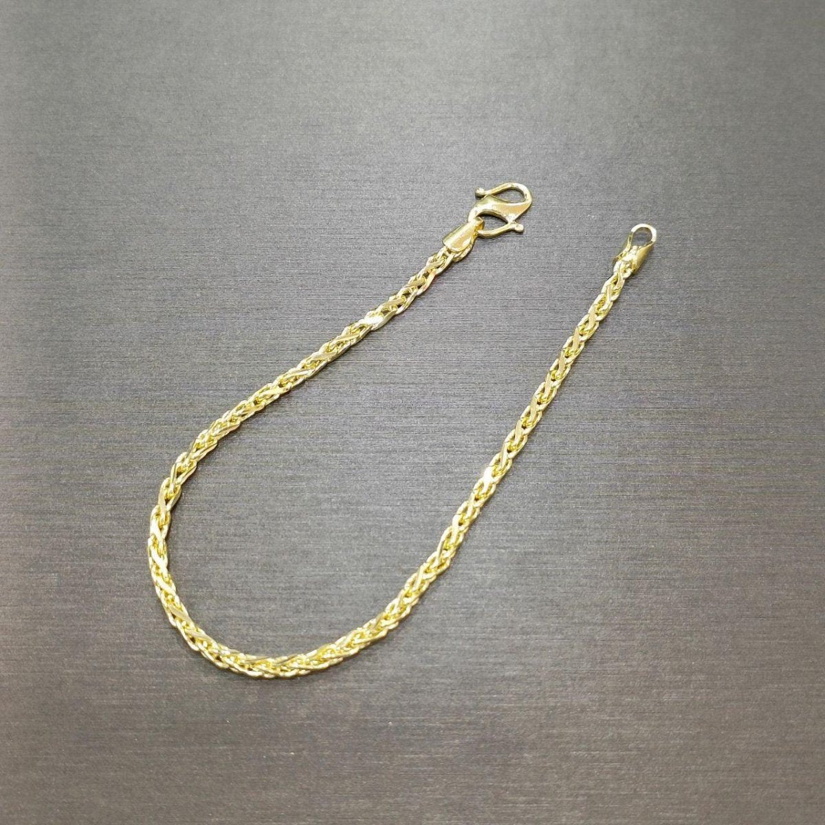 BR9028 916 gold Scale Bracelet V3 open on a grey surface, showing interwoven links and lobster clasp