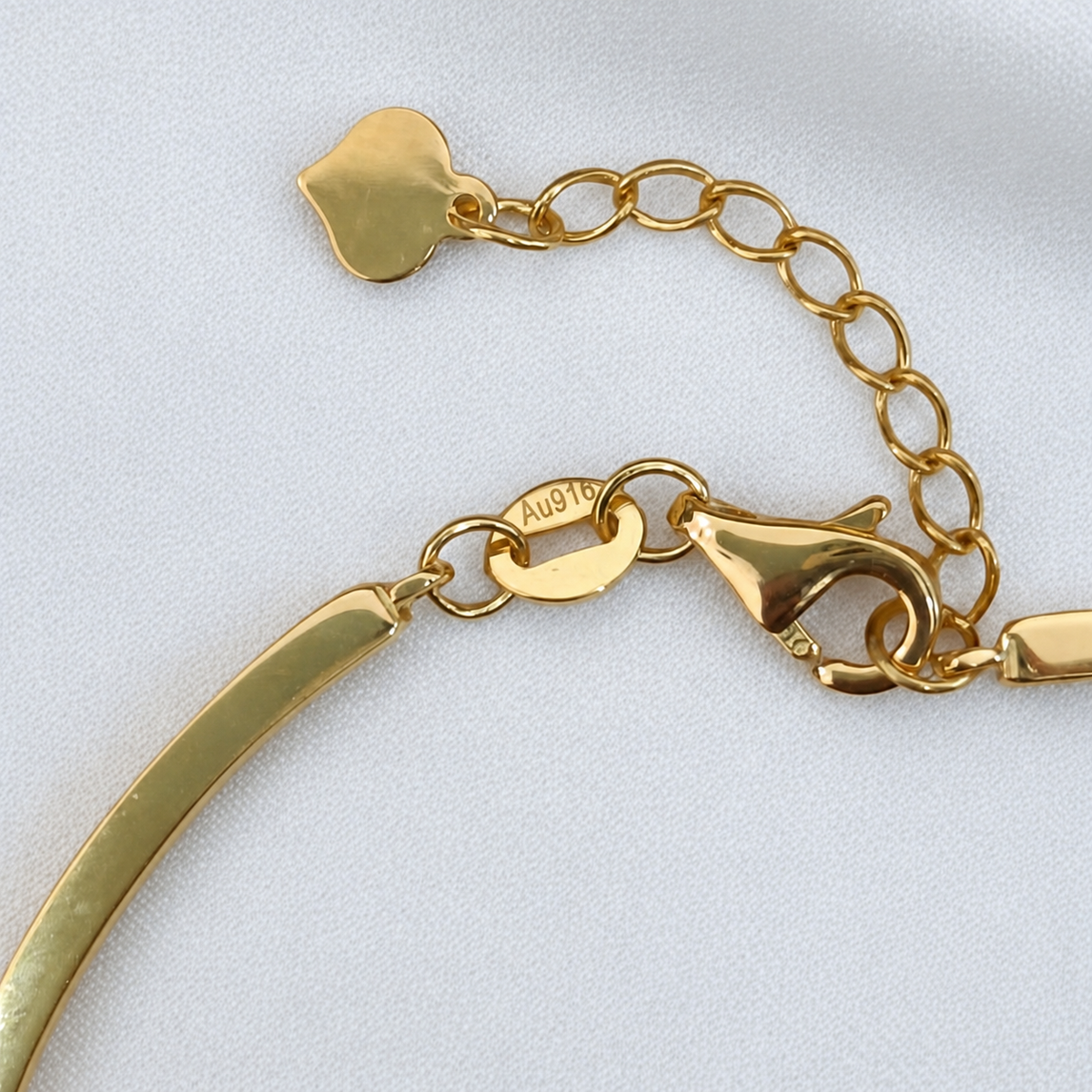 Close-up of the adjustable 916 gold bangle lobster clasp, extension chain and metal purity marking