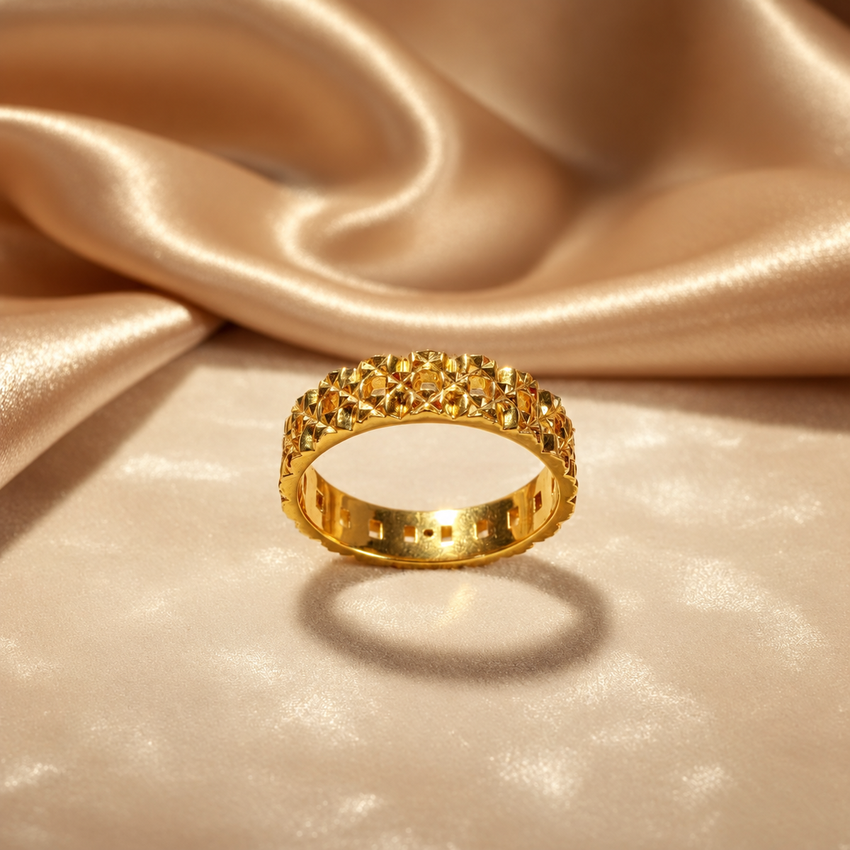 Front view of the 916 gold Slim Keeper ring on gold satin showing geometric facets and openwork