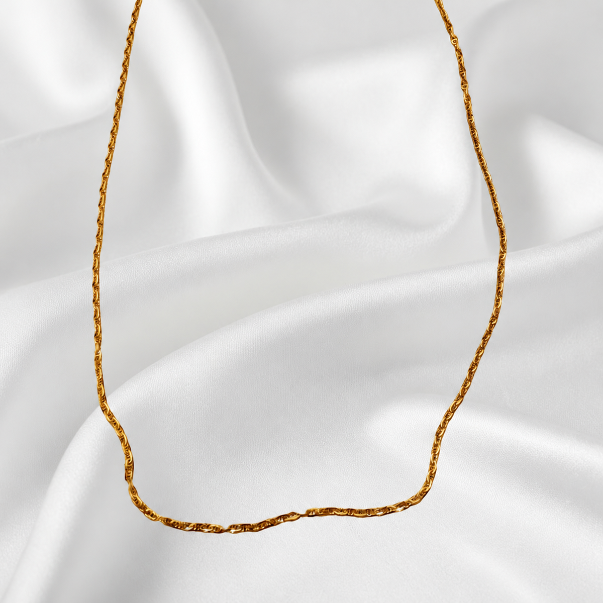 Guild Bullion 916 gold necklace detail showing the slim twisted link chain against white satin