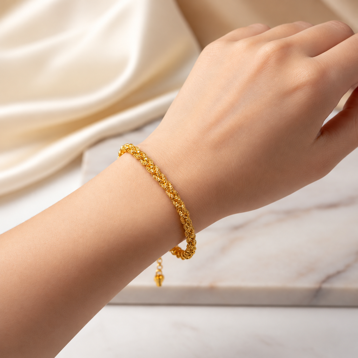 916 gold Wave Braided Bracelet worn on a wrist against cream satin, shown as a styling reference