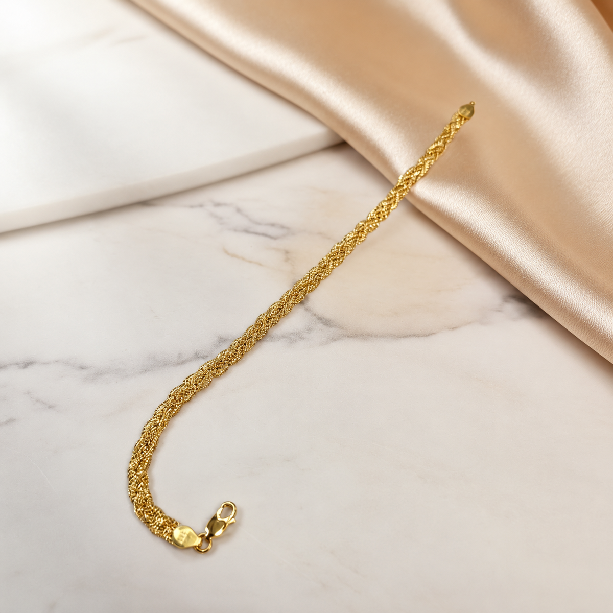 916 gold Wave Braided Bracelet extended diagonally over white marble and cream satin