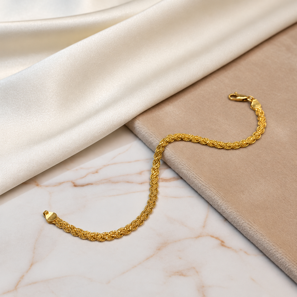 916 gold Wave Braided Bracelet arranged over marble and a beige display beside cream satin