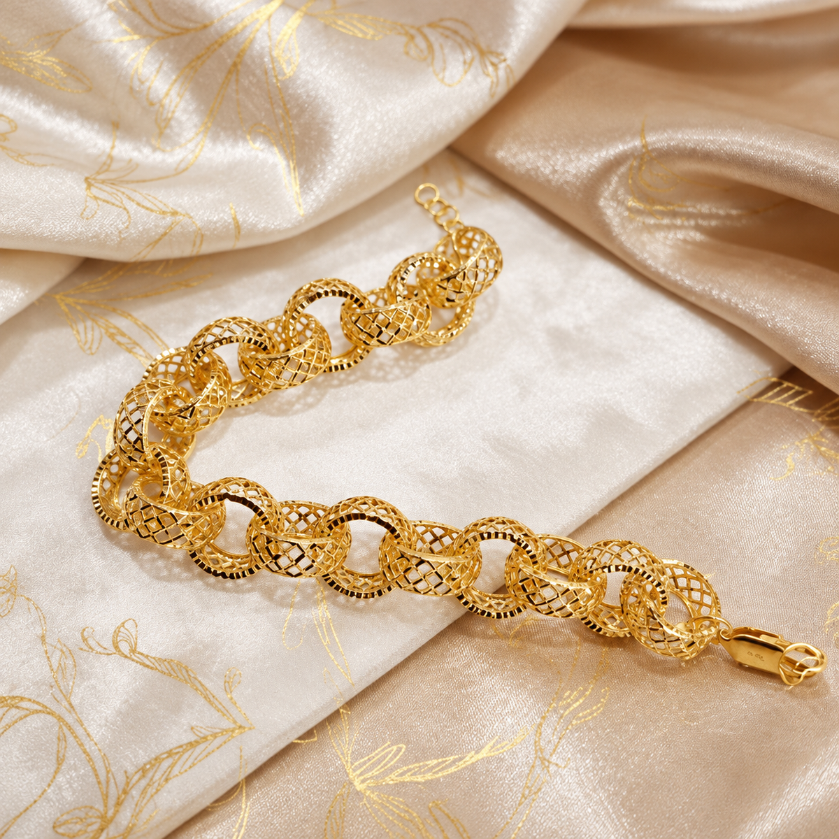 916 gold Wave Ring Bracelet extended across patterned cream satin showing lattice-cut ring links