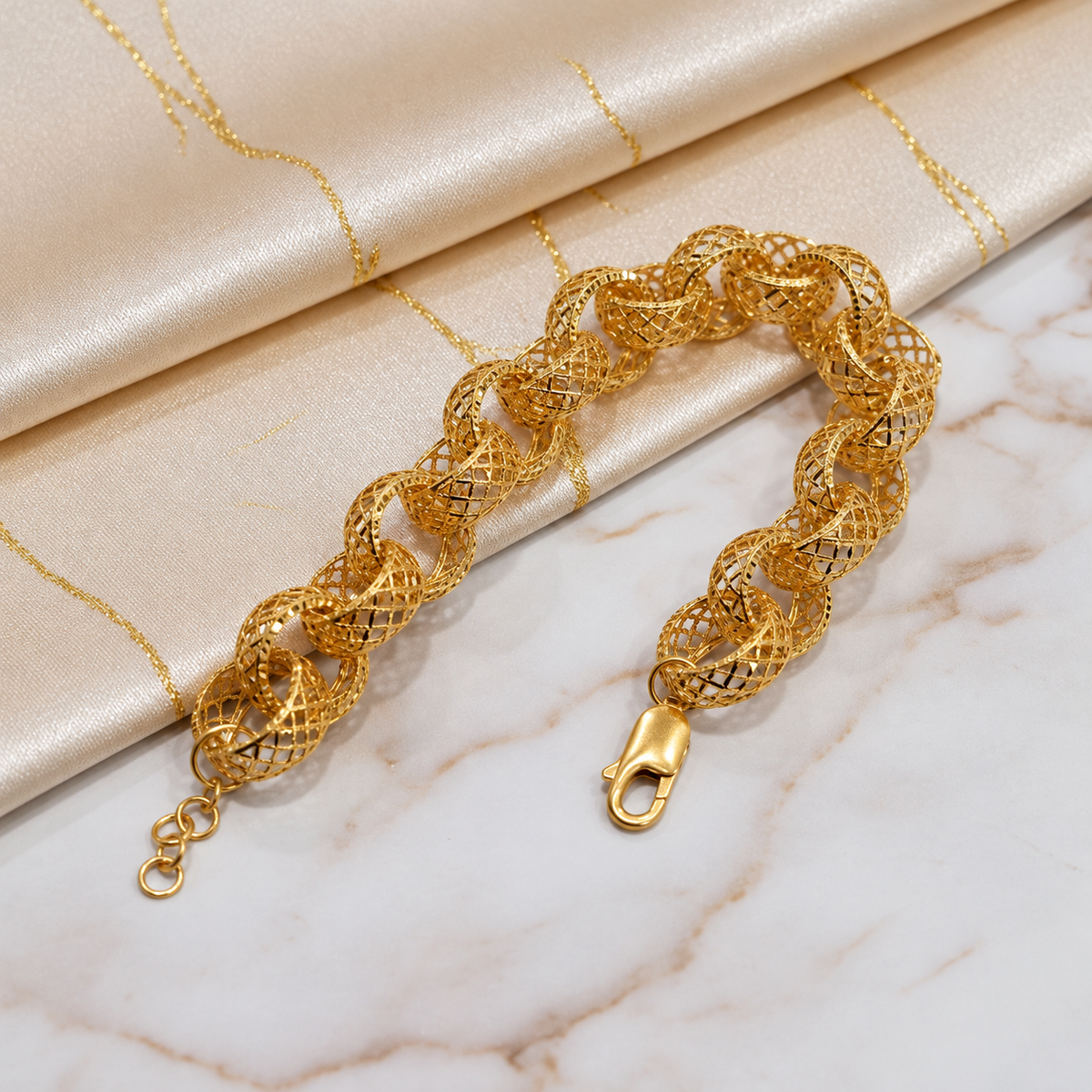 916 gold Wave Ring Bracelet on marble beside satin with lobster clasp in the foreground