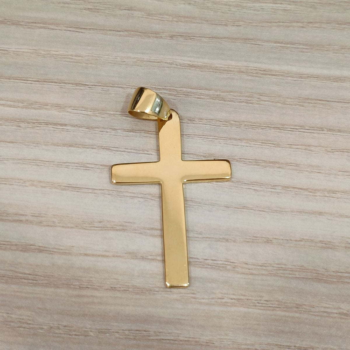 22K gold cross pendant shown upright with its smooth surface and bail