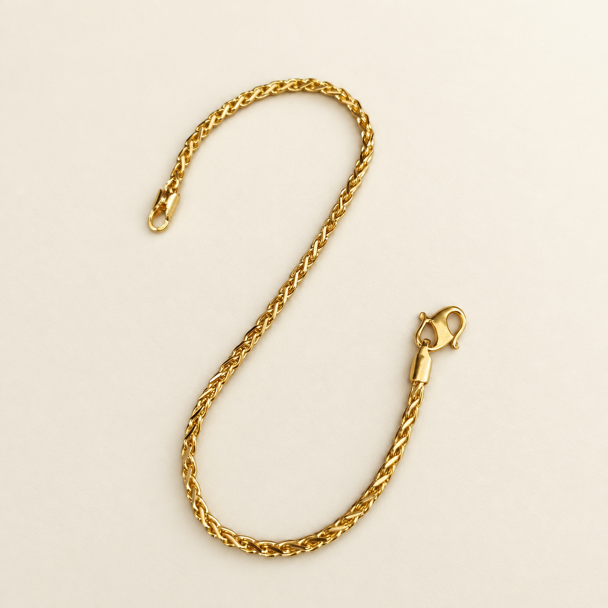 22K / 916 gold Spike Bracelet laid in a curve, showing interlocking diagonal links and lobster clasp